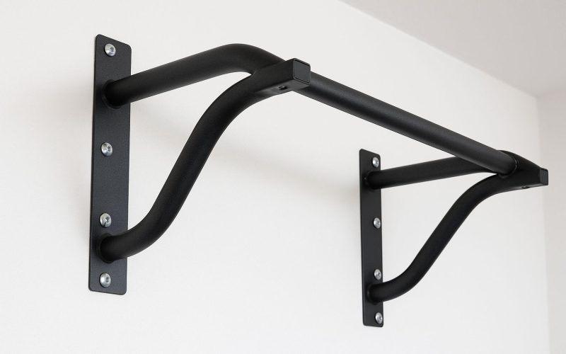 En man tränar chins med en pull up-stång i en dörröppning.